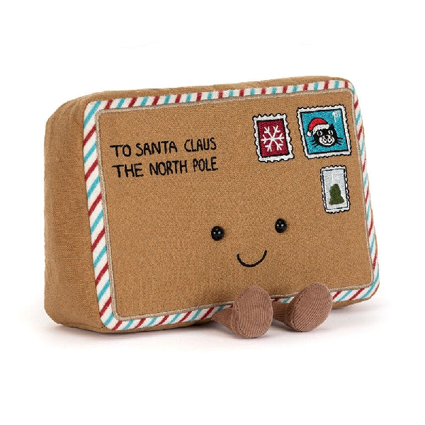 Front view of a Jellycat brown envelope shaped plush addressed to Santa Claus with a red and blue striped border, embroidered stamps and a smiling face on a white background