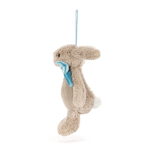 Side view of a Jellycat beige plush bunny ornament with a blue bow on a white background