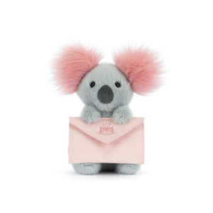 Front view of a Jellycat grey plush koala toy with pink ears holding a pink envelope on a white background
