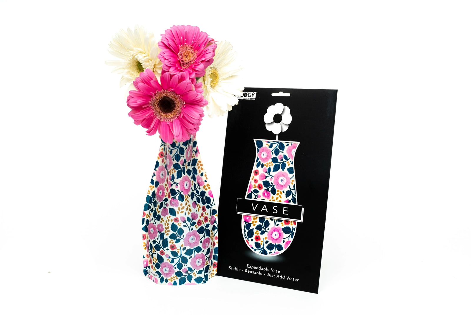 Expandable vase with a pink and blue floral design filled with a bouquet of pink and white flowers. The vase is placed beside it's packaging with Modgy branding on a white background. 