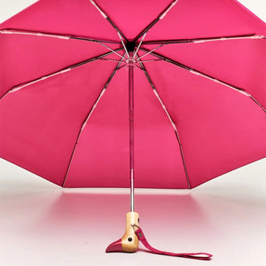 Opened pink umbrella with a wooden handle and duck shaped handle on a white background.