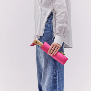 Person holding a closed pink umbrella with a duck shaped wooden head on a white background.