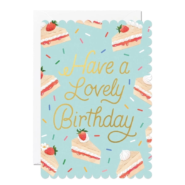 Greeting card with a scalloped edge featuring strawberry cake slice designs on a blue background with the text 'Have a Lovely Birthday'. 