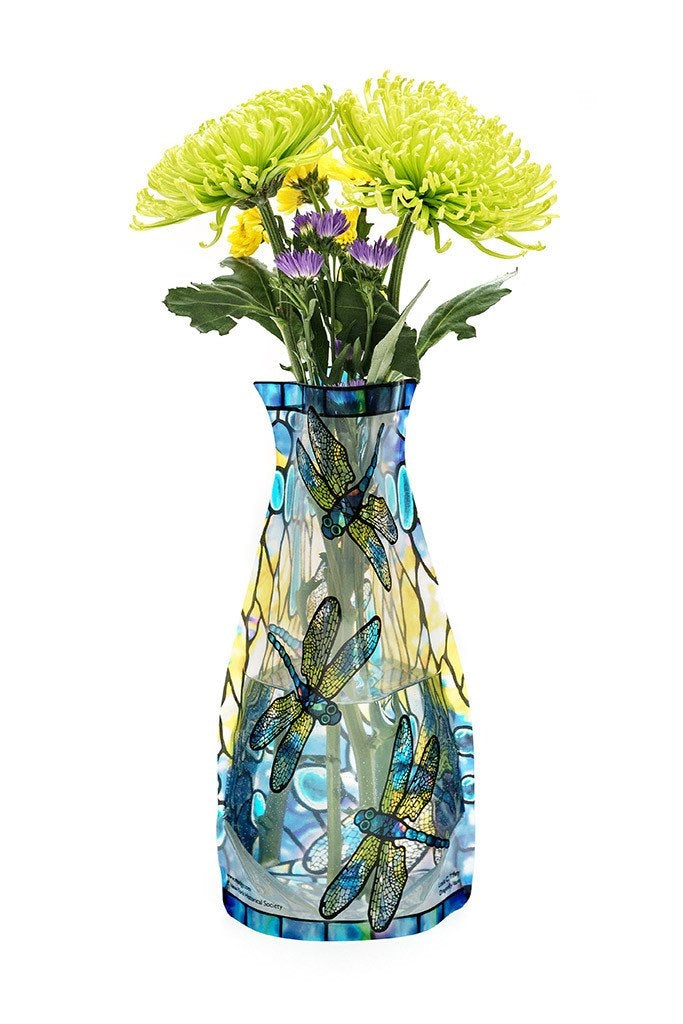 Expandable vase with a yellow and blue dragonfly design filled with a bouquet of flowers on a white background. 