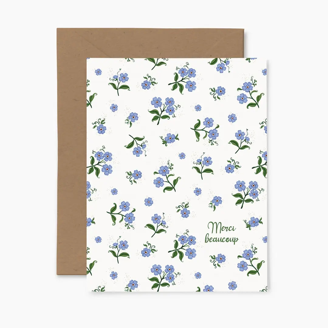 Greeting card featuring a blue floral pattern and 'Merci beaucoup' text, with a brown envelope on a white background.