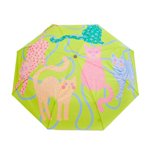 Opened green umbrella with an abstract cat print and a wooden duck head shaped handle on a white background. 