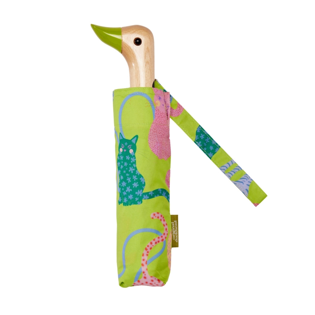 Green umbrella with an abstract cat print and a wooden duck head shaped handle on a white background. 