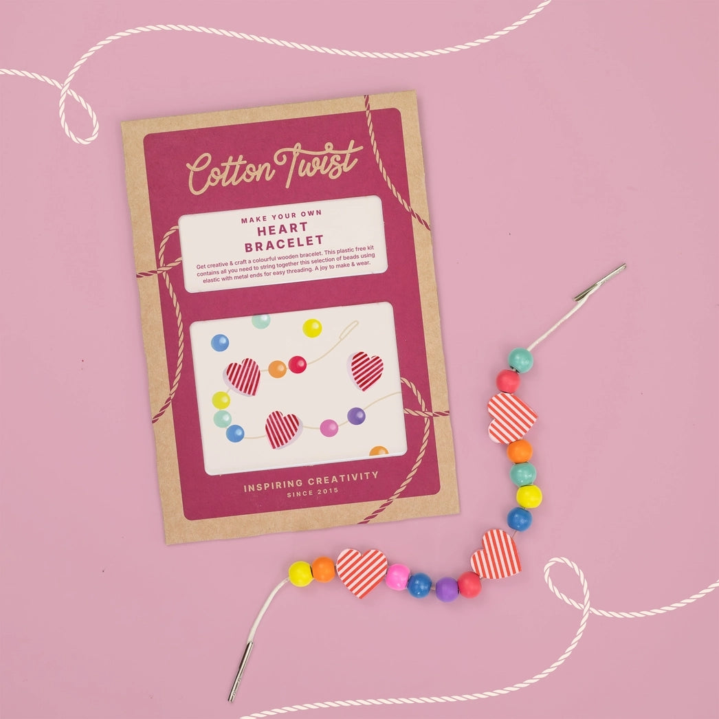 Colorful heart bracelet with packaging on a pink background.