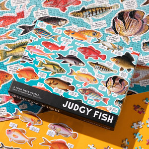 Packaging for a colourful fish themed puzzle with funny text, sitting on top of a completed puzzle.