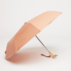 Opened brown umbrella with a wooden duck head shaped handle on a white background. 