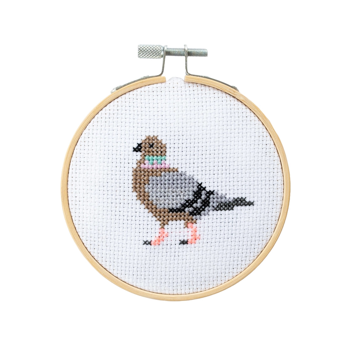 Cross-stitched pigeon design in a wooden hoop on a white background.