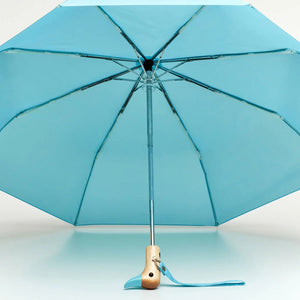 Open view of the inside of a Blue umbrella with a wooden duck head shaped handle on a white background. 