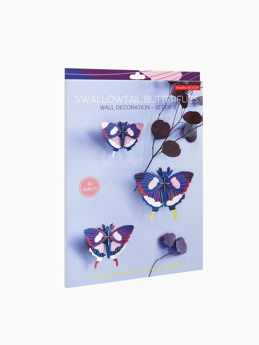 Packaging box for a swallowtail butterflies wall art kit from Studio Roof. The box features an image of three 3D butterflies hanging on a blue background. The butterflies are blue, pink, white, purple and red in colour. 