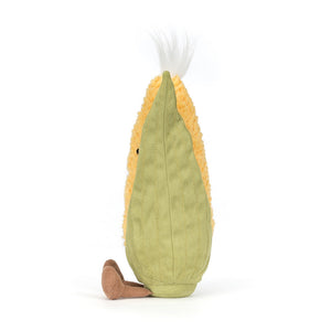 Side view of a Jellycat yellow and green corn on the cob shaped plush with a white tuft of hair on a white background