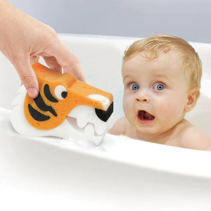 A tiger-shaped kids' bath sponge placed on a bath surface beside a baby.