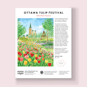 Back view of a jigsaw puzzle box featuring a beautiful illustrated scene from Ottawa's Tulip Festival, along with the company's branding and some text. 
