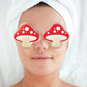 Gel eye pads in the shape of cartoon-like red mushrooms placed over a person's eyes.